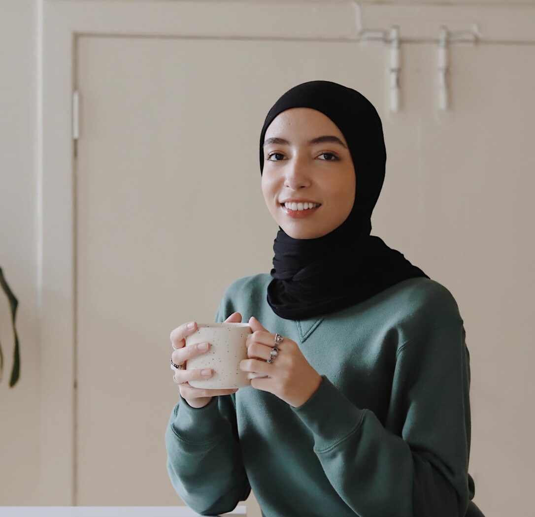 Women holding a coffee cup sitting at a table.