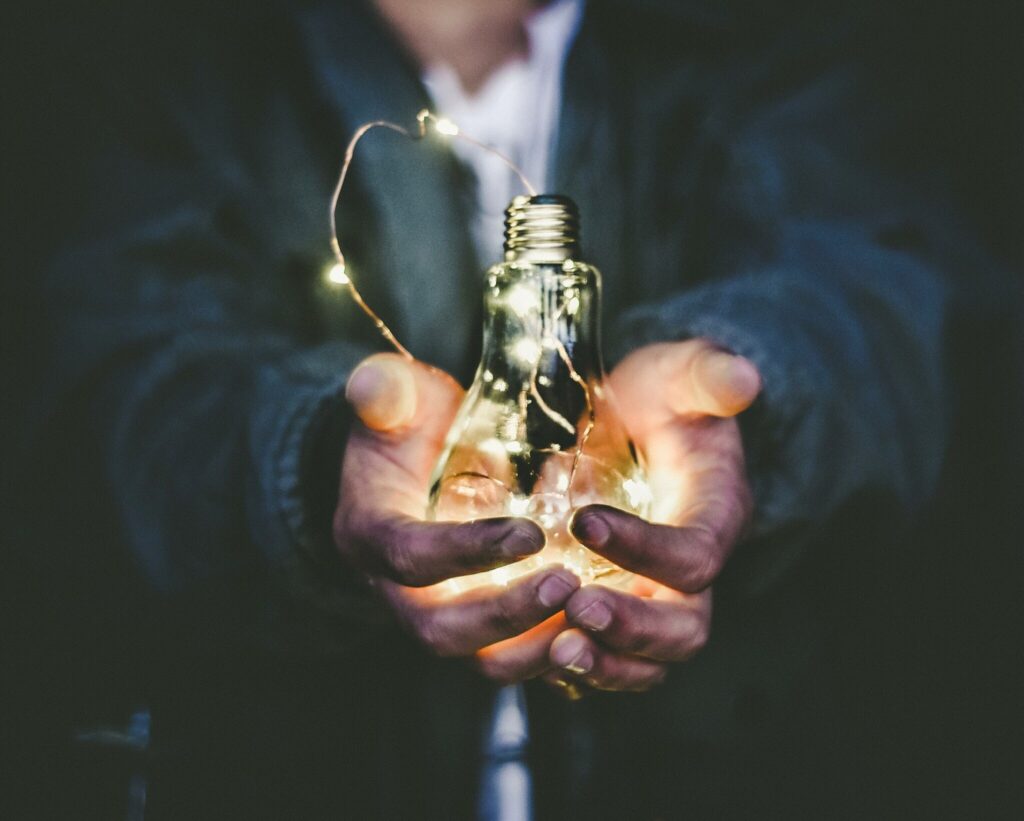 man in a suit holds illuminate lightbulb in his hands