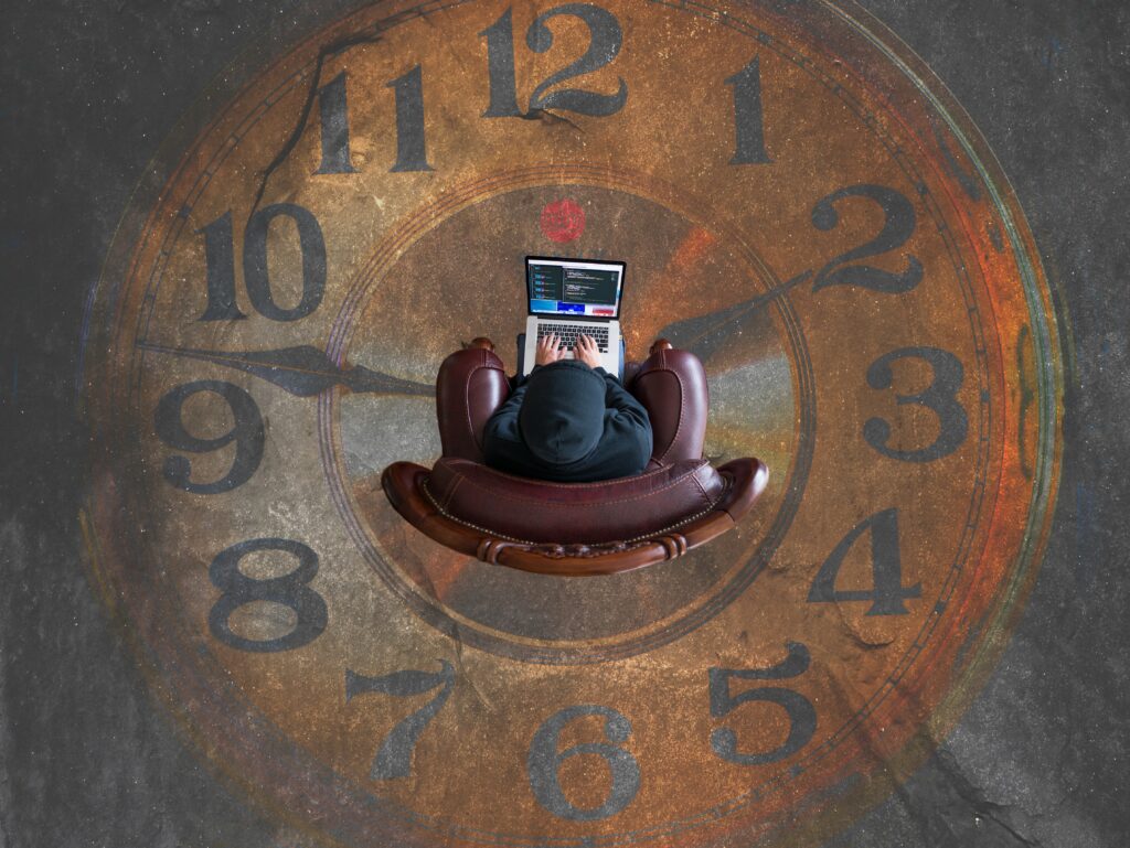 men sitting in the center of a giant clock, working on his computer